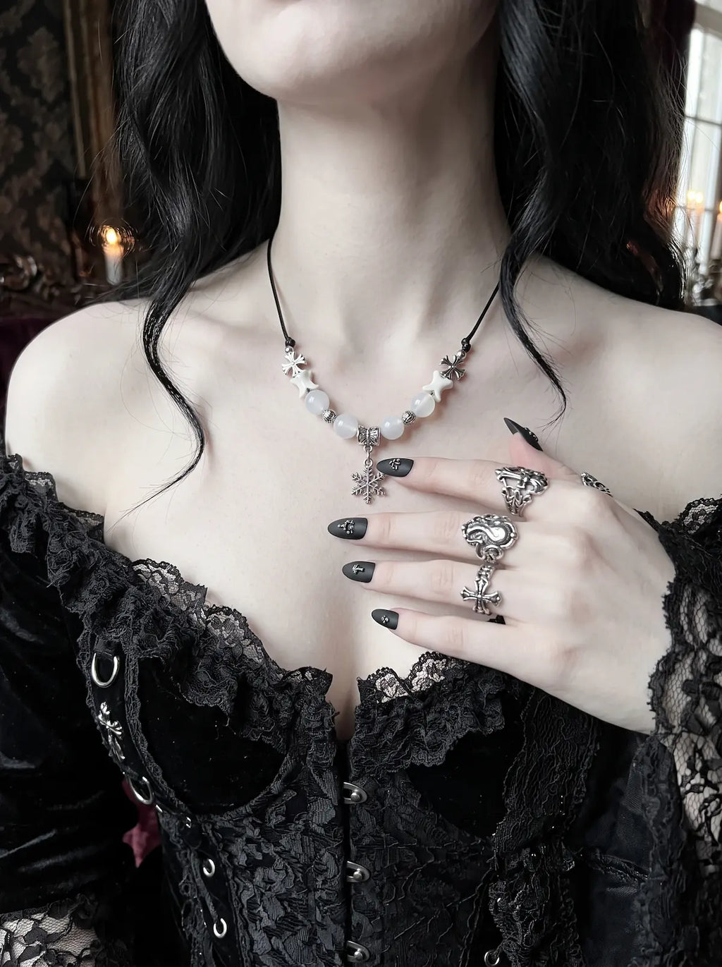Snowbound Snake Bone Necklace, snake bone necklace with dangling snowflake charm worn over dark clothing