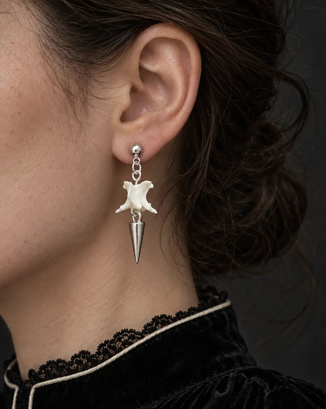 Short-spike Spire Chain snake bone earring shown close to the ear above a black lace collar