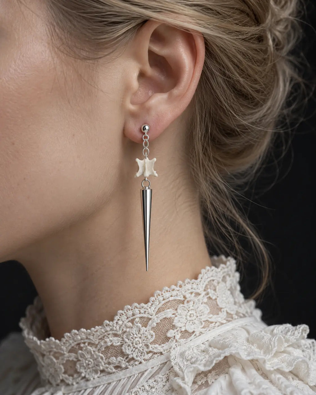 Long-spike Spire Chain snake bone earring shown in side profile above a white lace collar