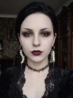 Split Relic Snake Bone Earrings, front portrait displaying both dangling bone earrings against a black outfit