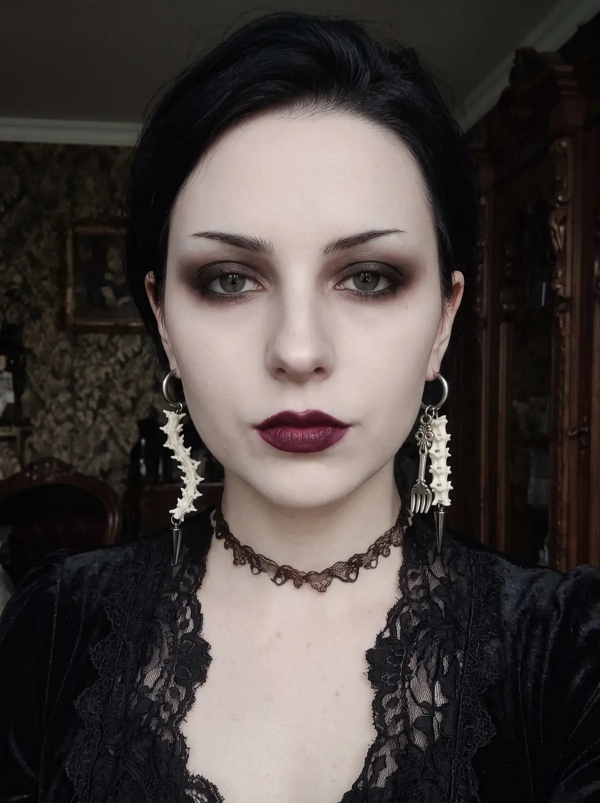 Split Relic Snake Bone Earrings, front portrait displaying both dangling bone earrings against a black outfit