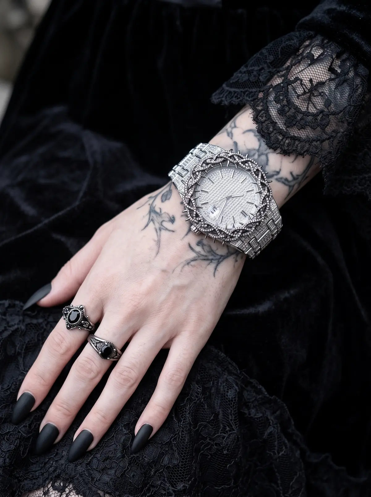 Thorncrown Gothic Watch, pale-dial thorn-bezel watch on a tattooed wrist with a black lace sleeve