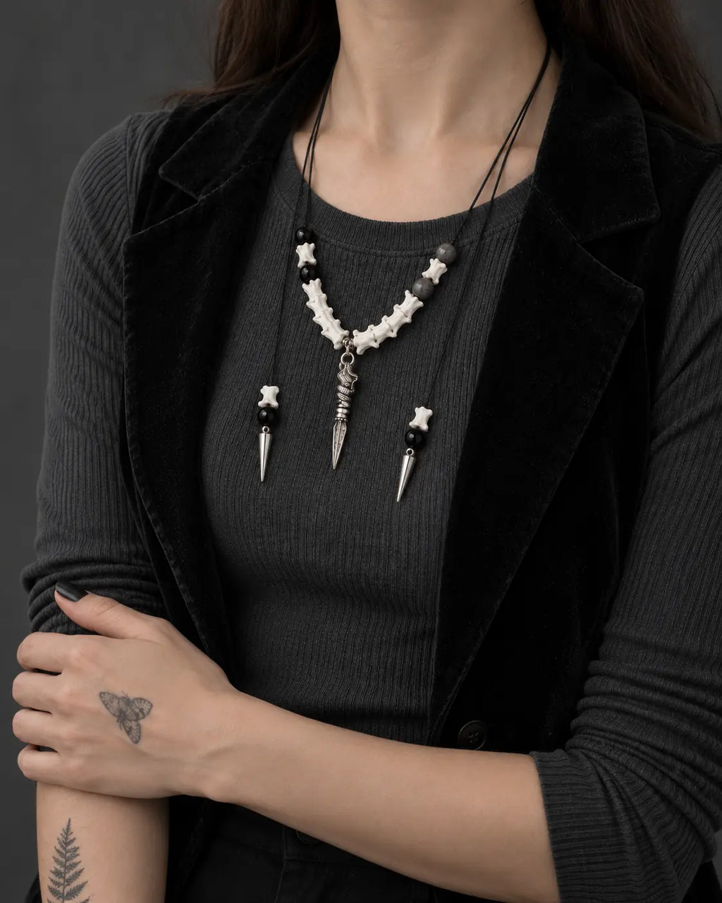 Threefold Talon snake bone necklace shown at chest level with the model's arms folded below