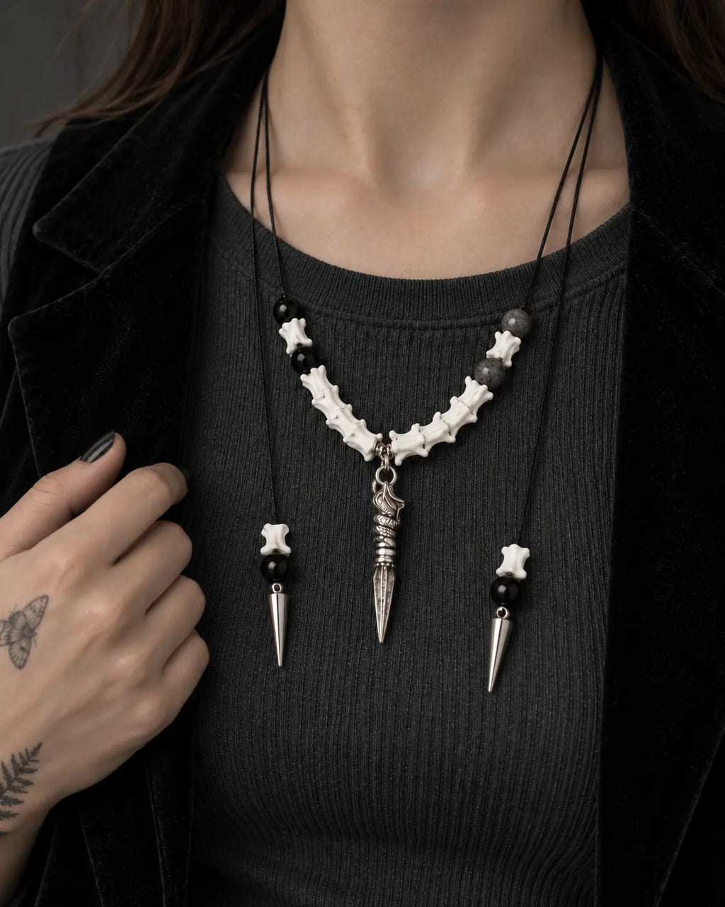 Close-up of the Threefold Talon snake bone necklace worn over a charcoal top, showing all three pointed drops