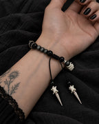 Palm-up view of the Twin Spike snake bone bracelet showing black beads, the sliding knot and two pointed drops