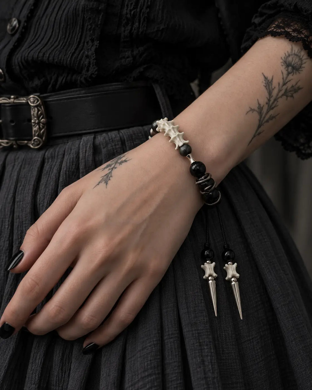 Twin Spike snake bone bracelet worn on a wrist against a dark pleated skirt, with both spikes hanging below