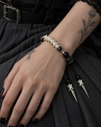 Top view of the Twin Spike snake bone bracelet on a hand resting over dark fabric