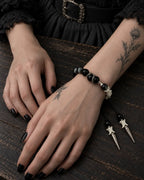 Twin Spike snake bone bracelet worn with both hands resting on a wooden table