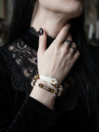 Umberblade Snake Bone Bracelet, close raised wrist view of preserved pale snake head and warm brown beads