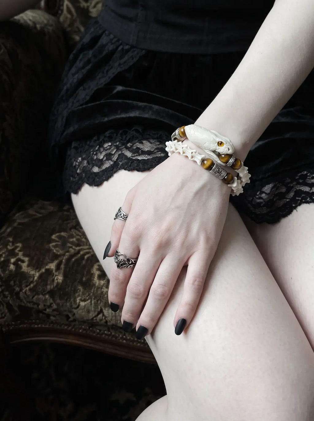 Umberblade Snake Bone Bracelet, wrist with pale snake head bracelet and gold-brown beads over black lace