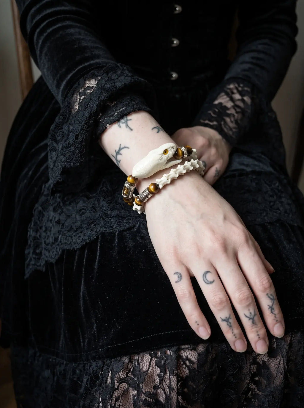 Umberblade Snake Bone Bracelet, amber accented snake bone bracelet worn on a wrist resting against dark fabric