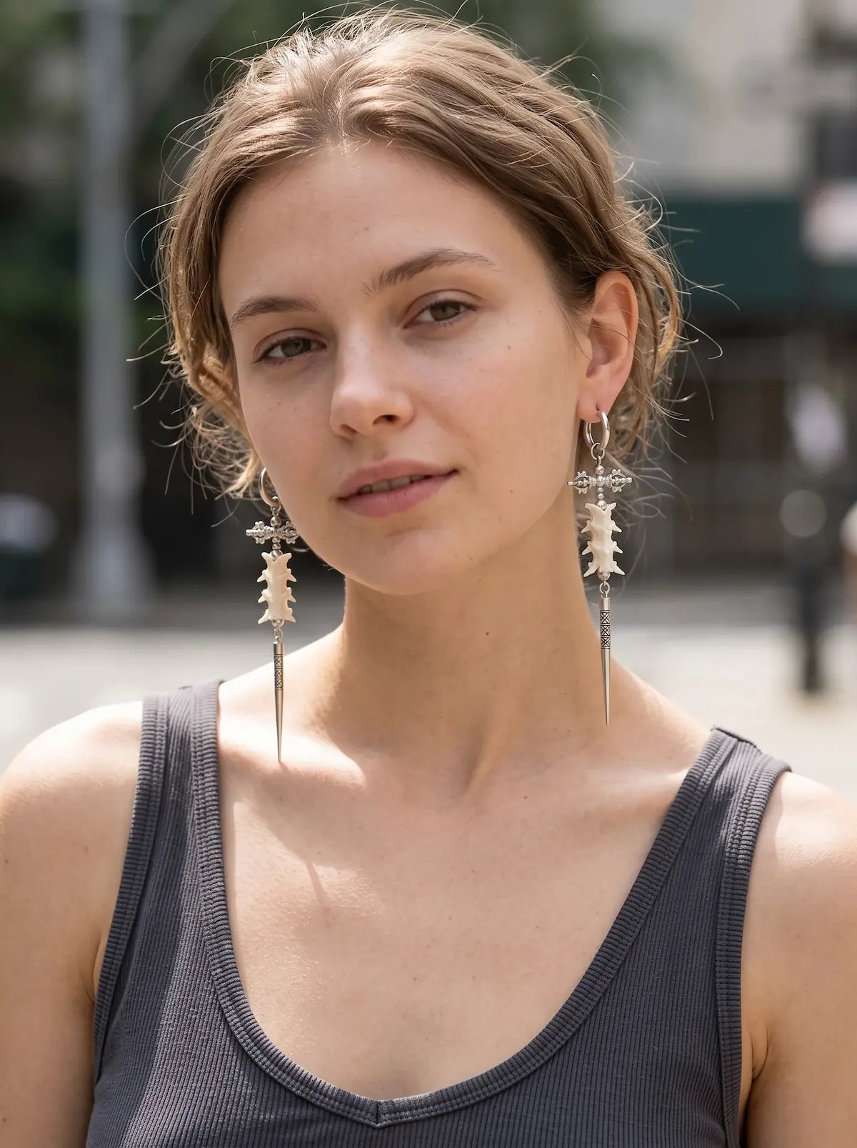 Vajra Spine snake bone earrings worn as a pair in a front-facing outdoor portrait