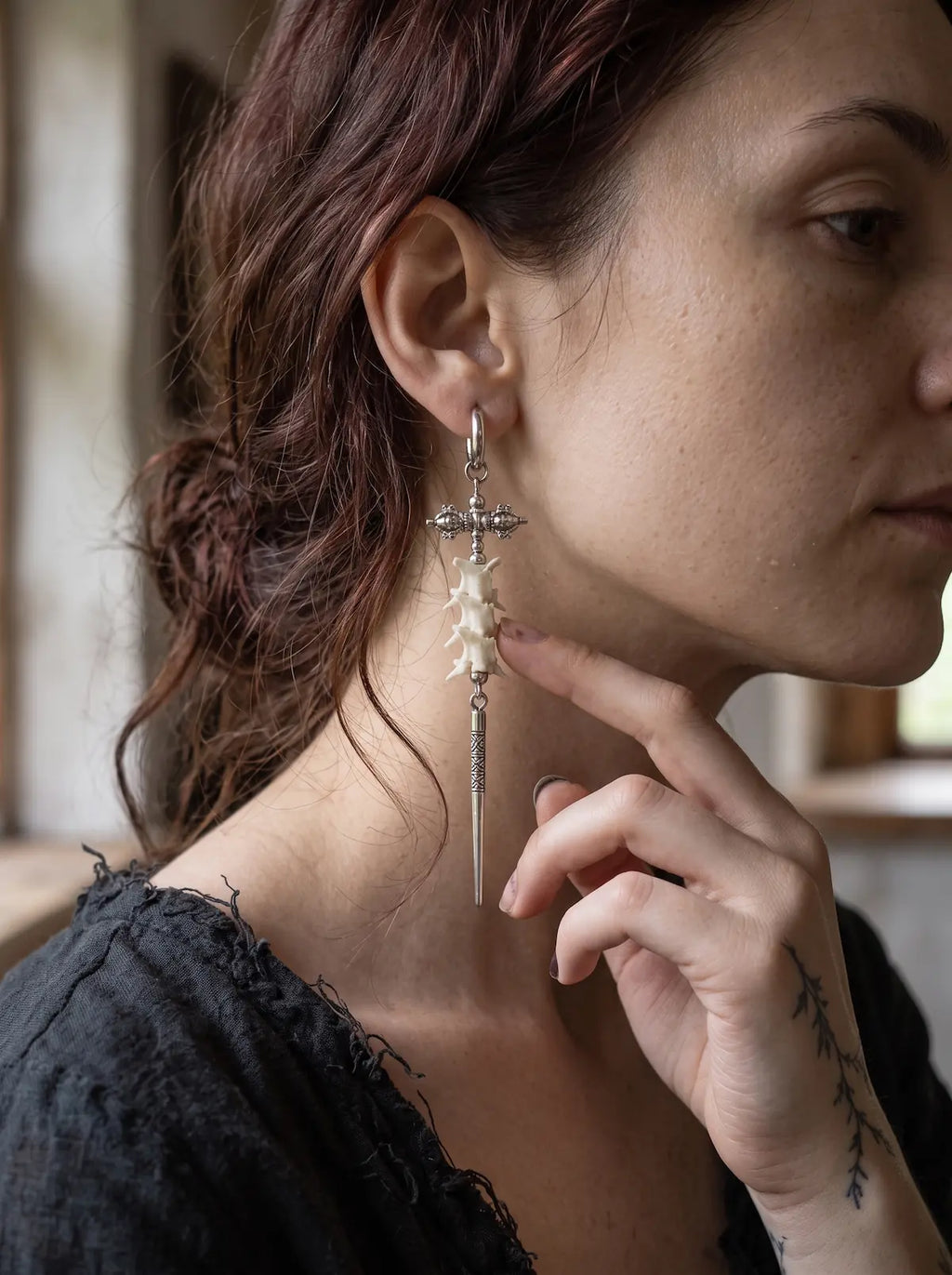 Vajra Spine snake bone earring shown in profile with a hand beneath the chin