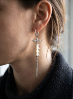 Close-up of a Vajra Spine earring showing white snake vertebrae and a long spike below the ear