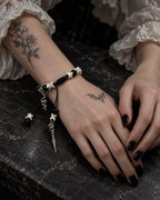 Venom Dagger snake bone bracelet on a wrist resting on a dark tabletop beside the other hand