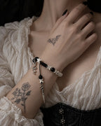 Venom Dagger snake bone bracelet worn with the hand at the collarbone above a cream blouse