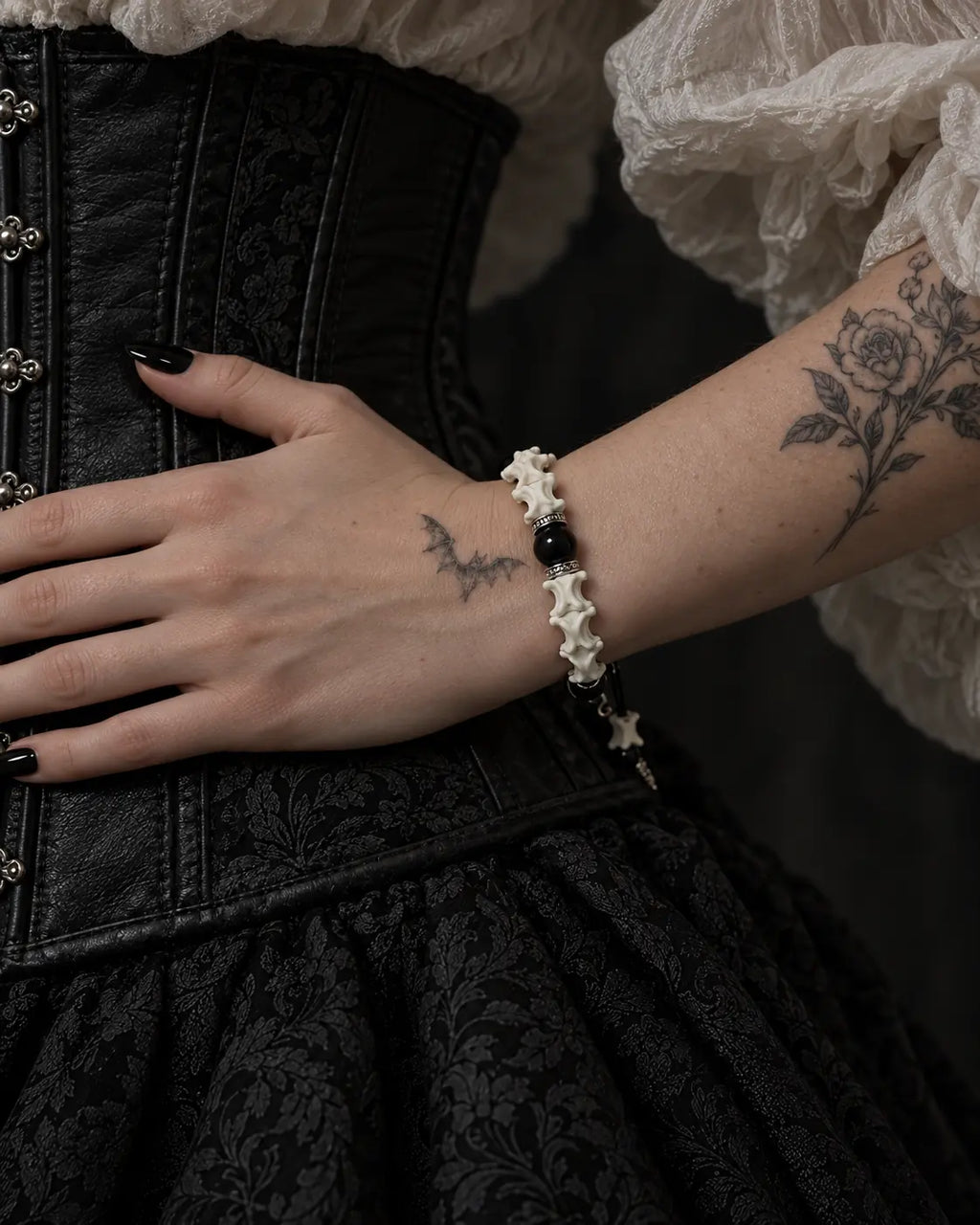 Side view of the Venom Dagger snake bone bracelet with the hand resting across a black corset