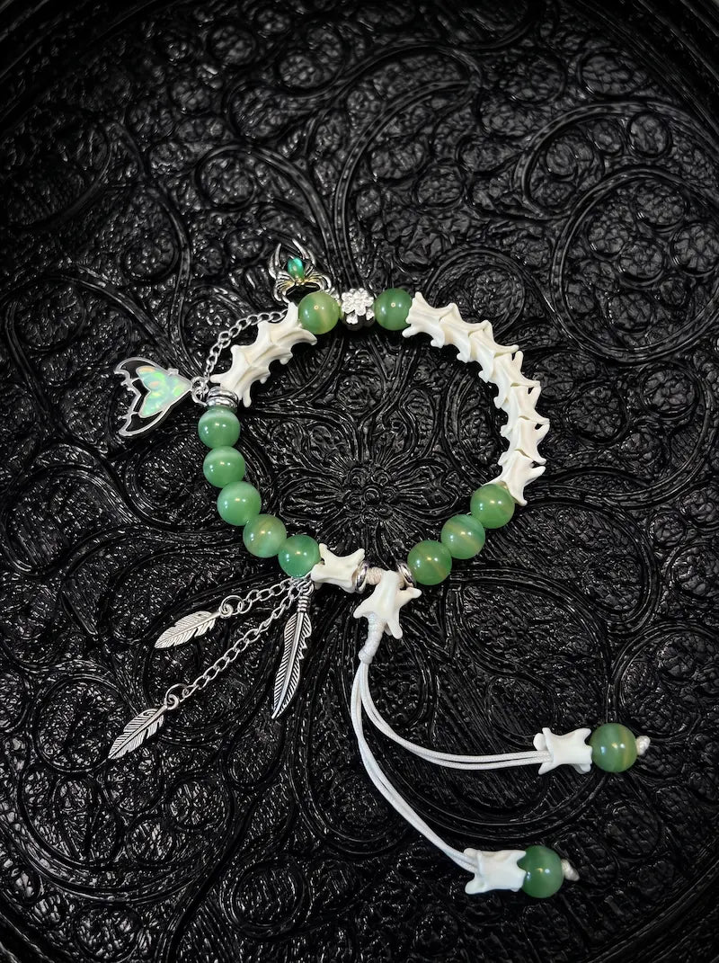 Verdant Feather snake bone bracelet with green beads, silver-tone feather drops, an iridescent wing charm and white cords