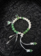 Verdant Feather snake bone bracelet with green beads, silver-tone feather drops, an iridescent wing charm and white cords