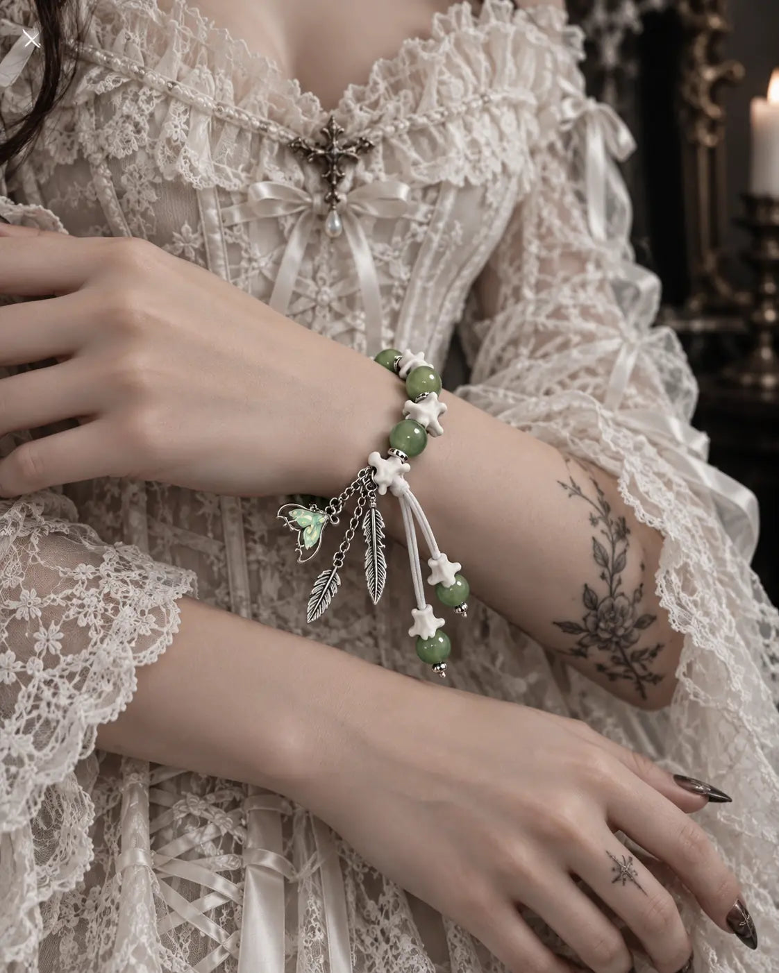Verdant Feather snake bone bracelet worn across folded arms over a white lace dress