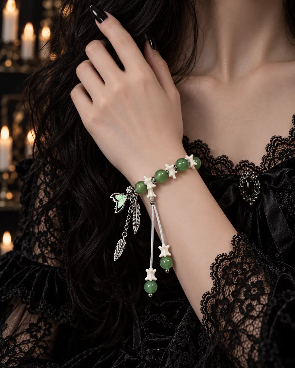 Verdant Feather snake bone bracelet worn with the hand at a black lace neckline, showing green beads and white vertebrae