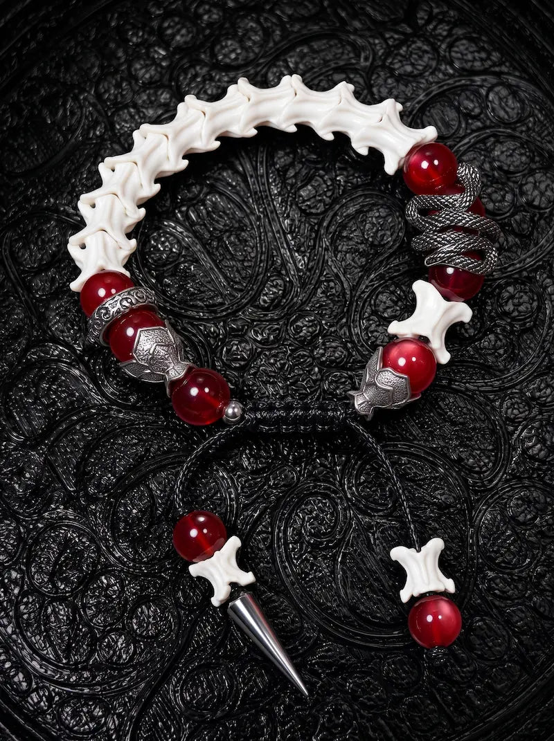 Vermilion Fang snake bone bracelet with red beads, a coiled serpent accent and a pointed metal drop on black cords