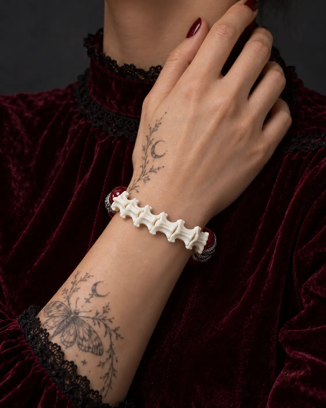 Vermilion Fang snake bone bracelet worn with the hand at the neck, showing the curved row of white vertebrae
