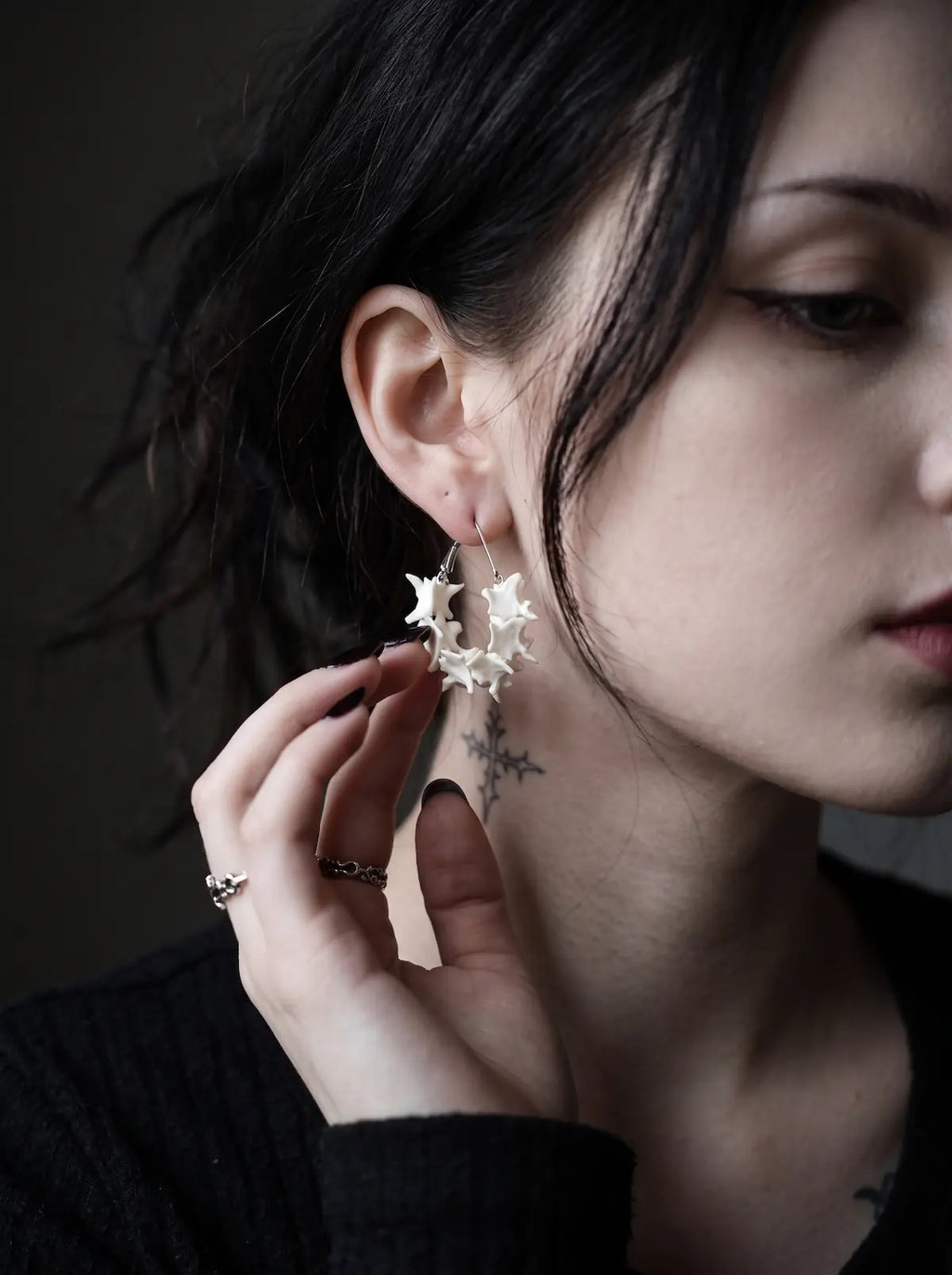 Vertebra Crescent snake bone earring worn with a hand resting near the jaw