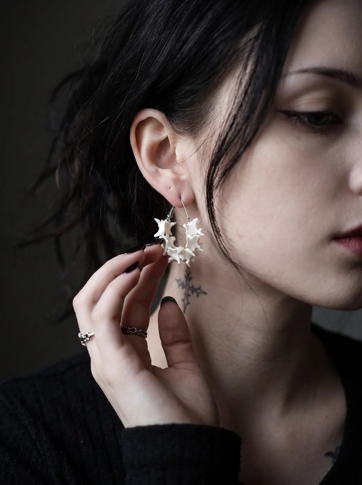 Vertebra Crescent snake bone earring worn with a hand resting near the jaw