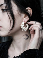 Vertebra Crescent snake bone earring worn with a ringed hand lifting the hair beside the ear