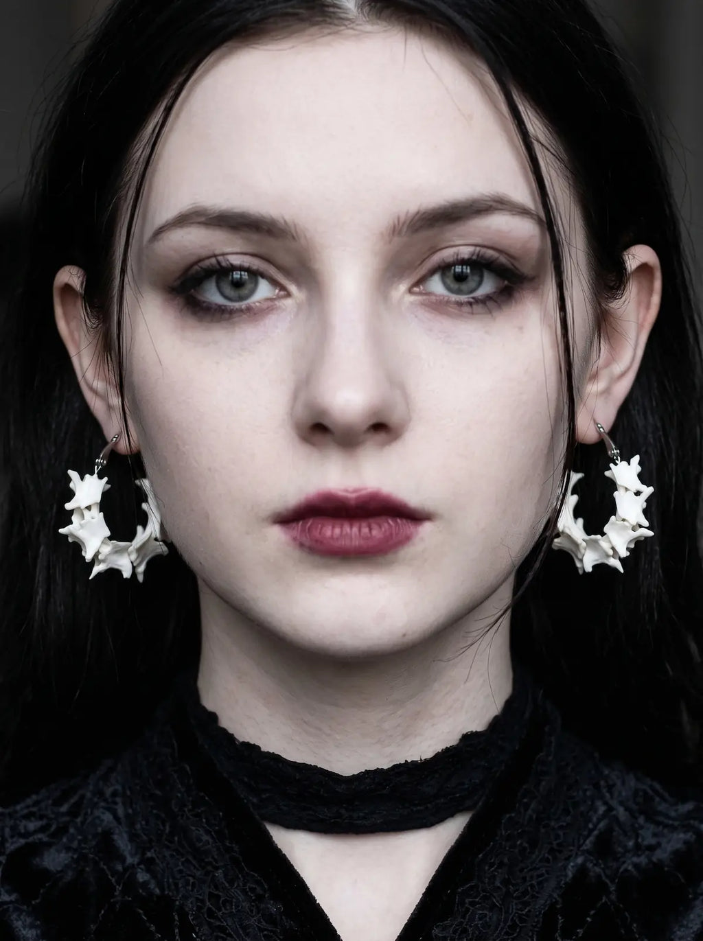 Vertebra Crescent snake bone earrings worn as a pair in a front-facing portrait with a black choker