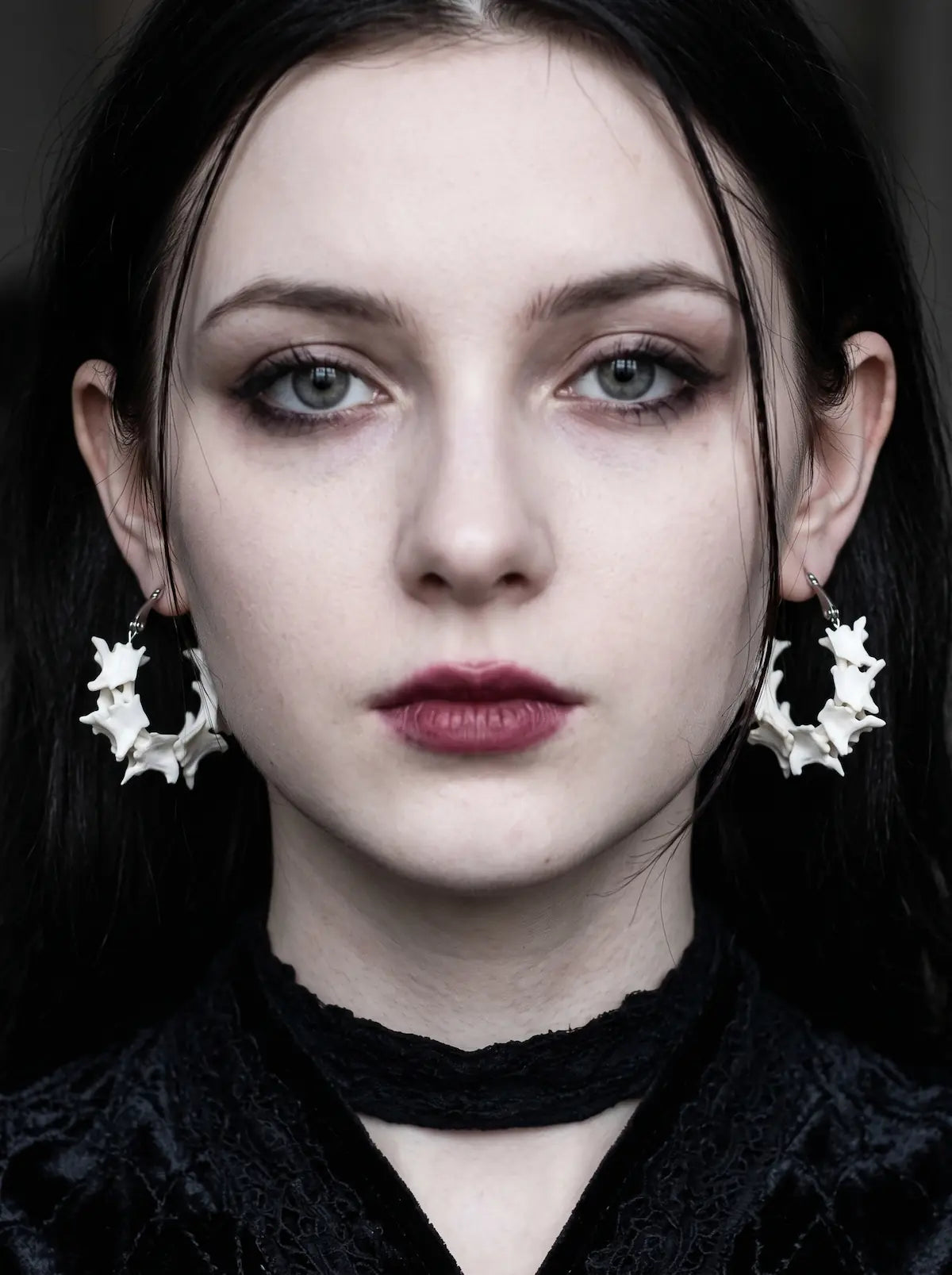 Vertebra Crescent snake bone earrings worn as a pair in a front-facing portrait with a black choker