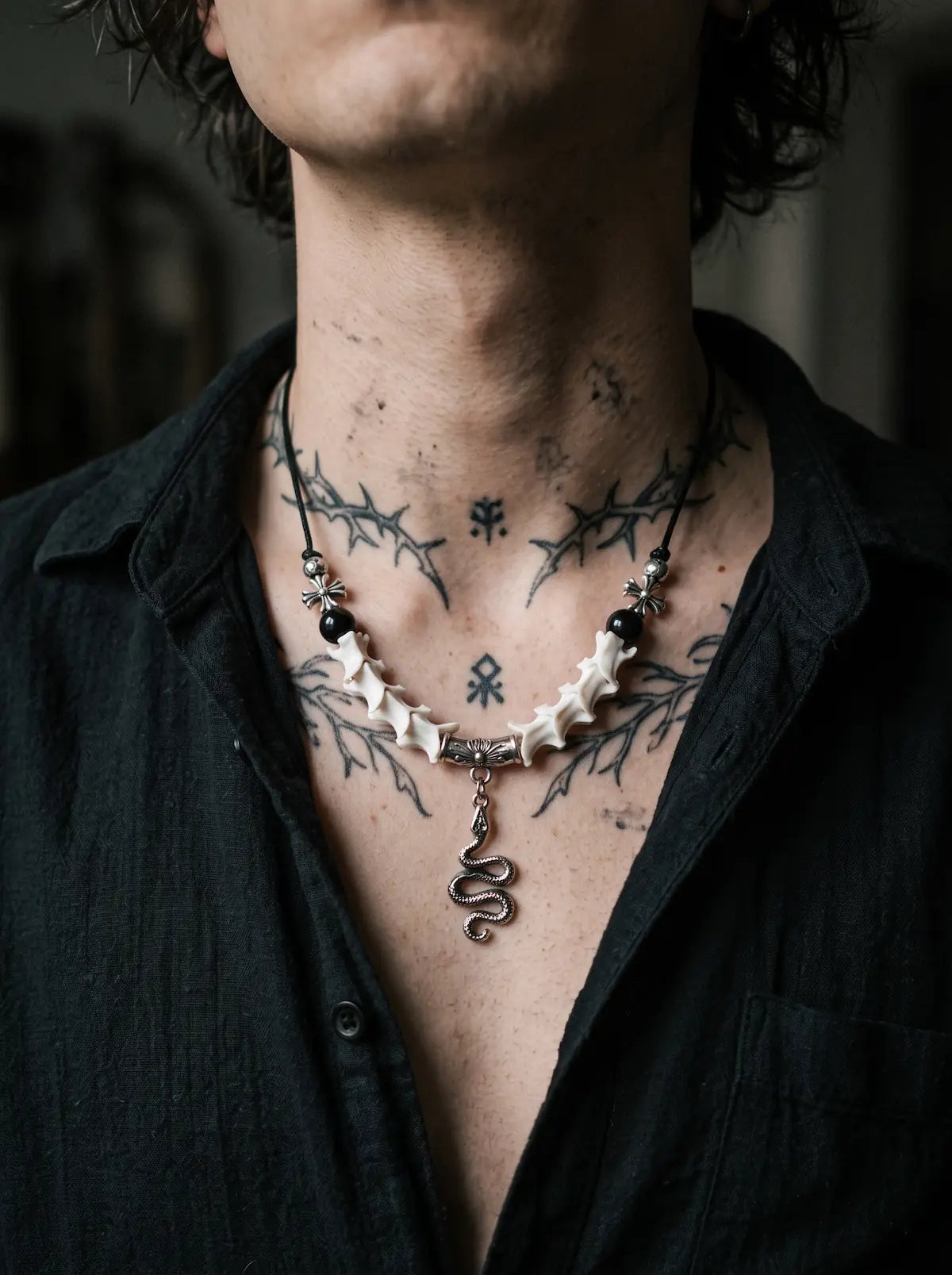 Vesper Serpent Snake Bone Necklace, snake bone and serpent pendant necklace worn against a tattooed chest