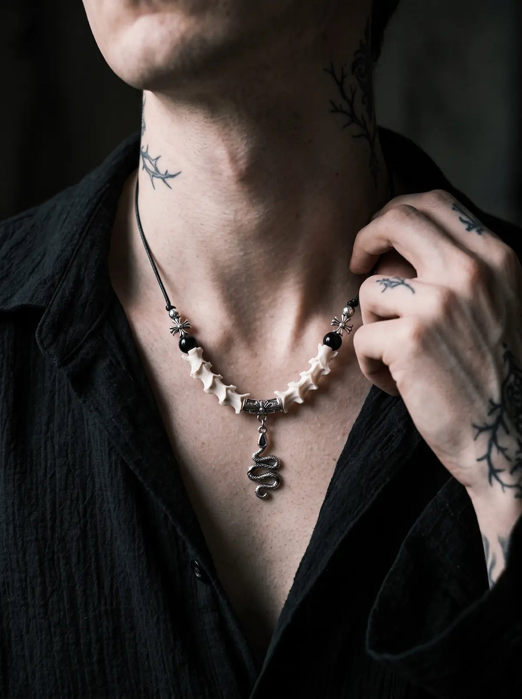 Vesper Serpent Snake Bone Necklace, close neck view of pale vertebrae necklace and dangling silver serpent charm