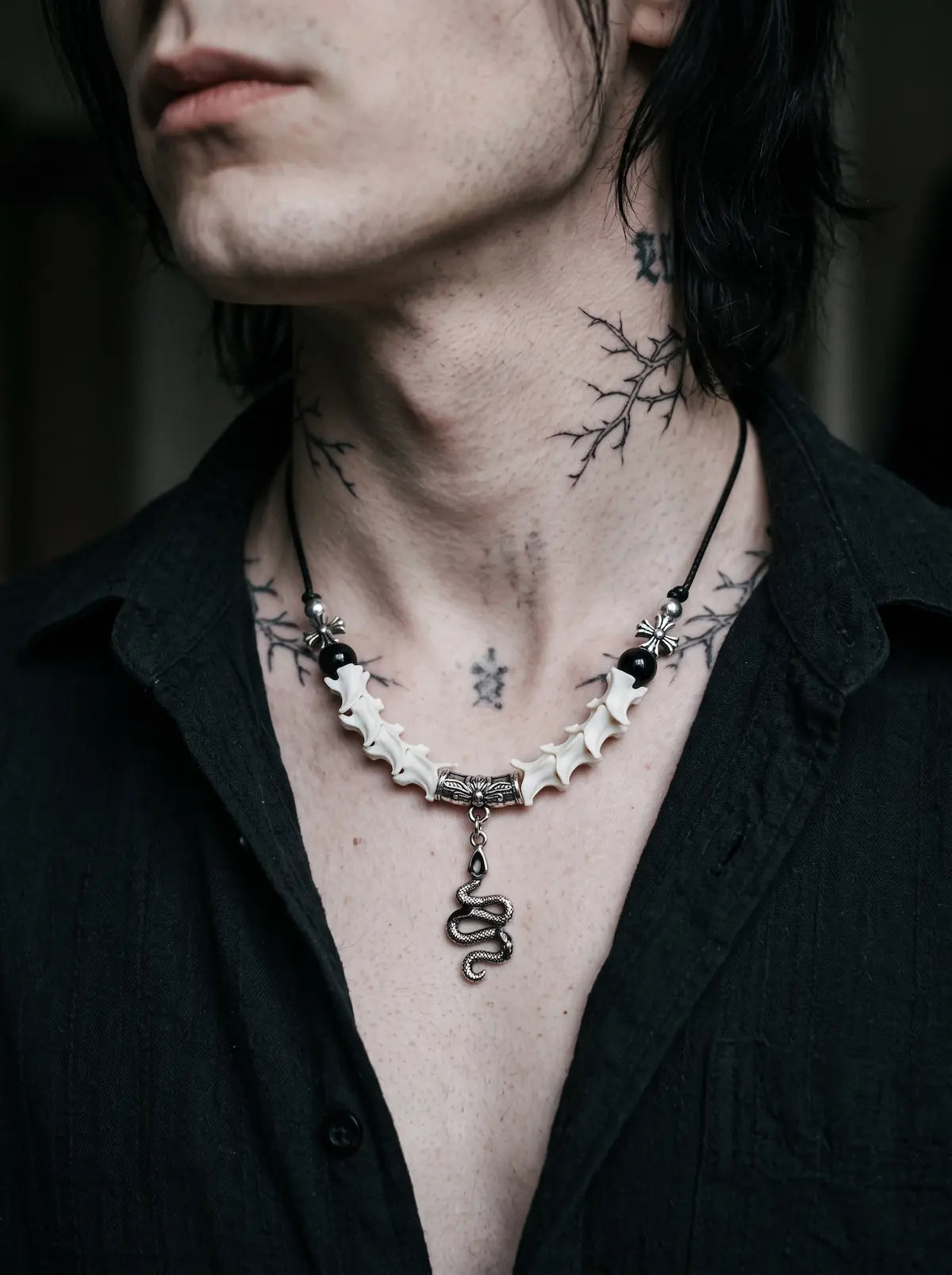 Vesper Serpent Snake Bone Necklace, snake vertebrae necklace with silver snake pendant worn above a black shirt
