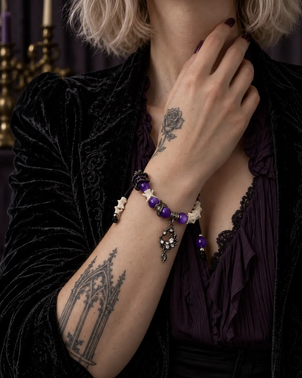 Violet Dragon snake bone bracelet worn with the hand near the neck above a purple blouse and black velvet jacket