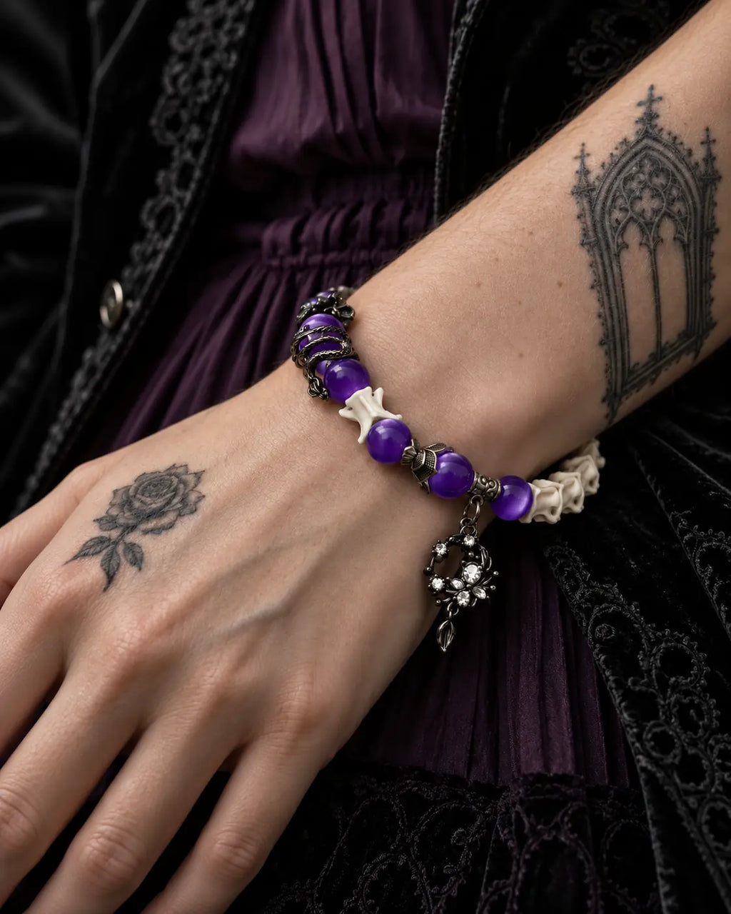 Close-up of the Violet Dragon snake bone bracelet showing glossy purple beads, a dragon accent and ornate crescent drop