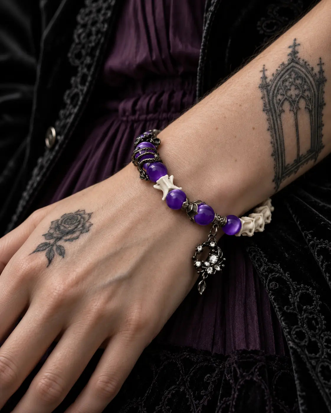 Close-up of the Violet Dragon snake bone bracelet showing glossy purple beads, a dragon accent and ornate crescent drop