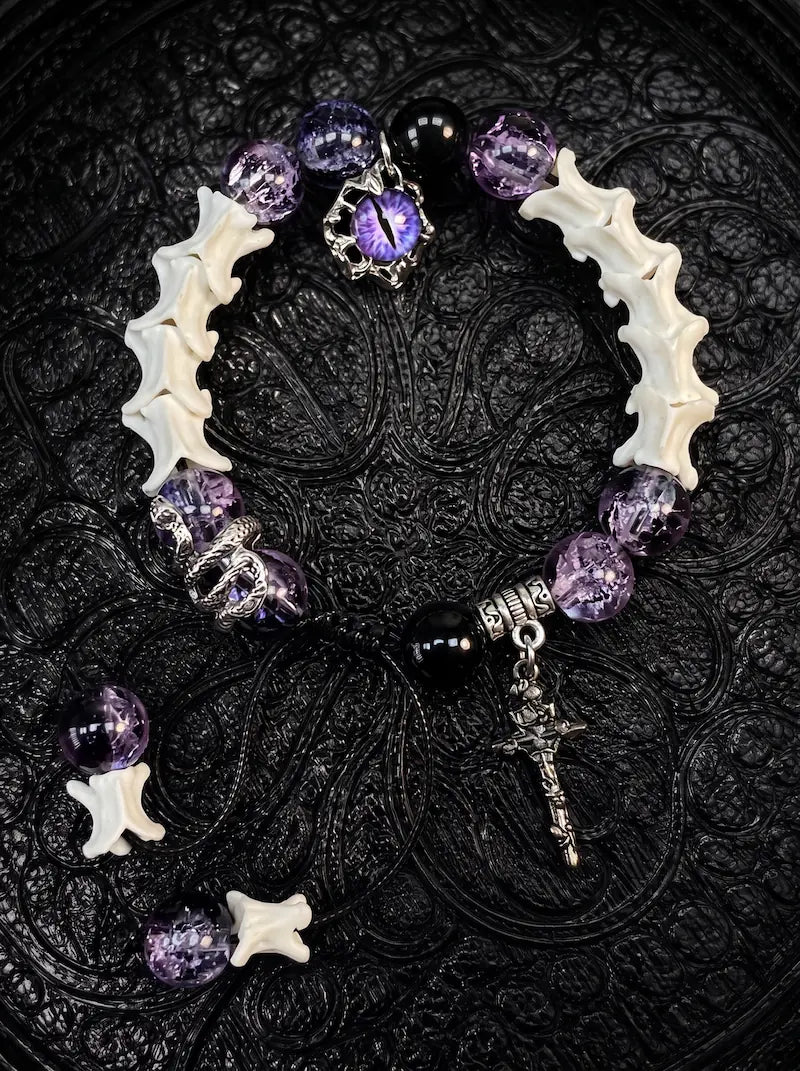 Violet Serpent Eye snake bone bracelet with purple beads, a coiled serpent, purple eye charm and a gothic cross
