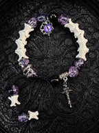 Violet Serpent Eye snake bone bracelet with purple beads, a coiled serpent, purple eye charm and a gothic cross