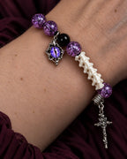 Close-up of the Violet Serpent Eye snake bone bracelet showing its purple eye charm, crackled beads and cross drop