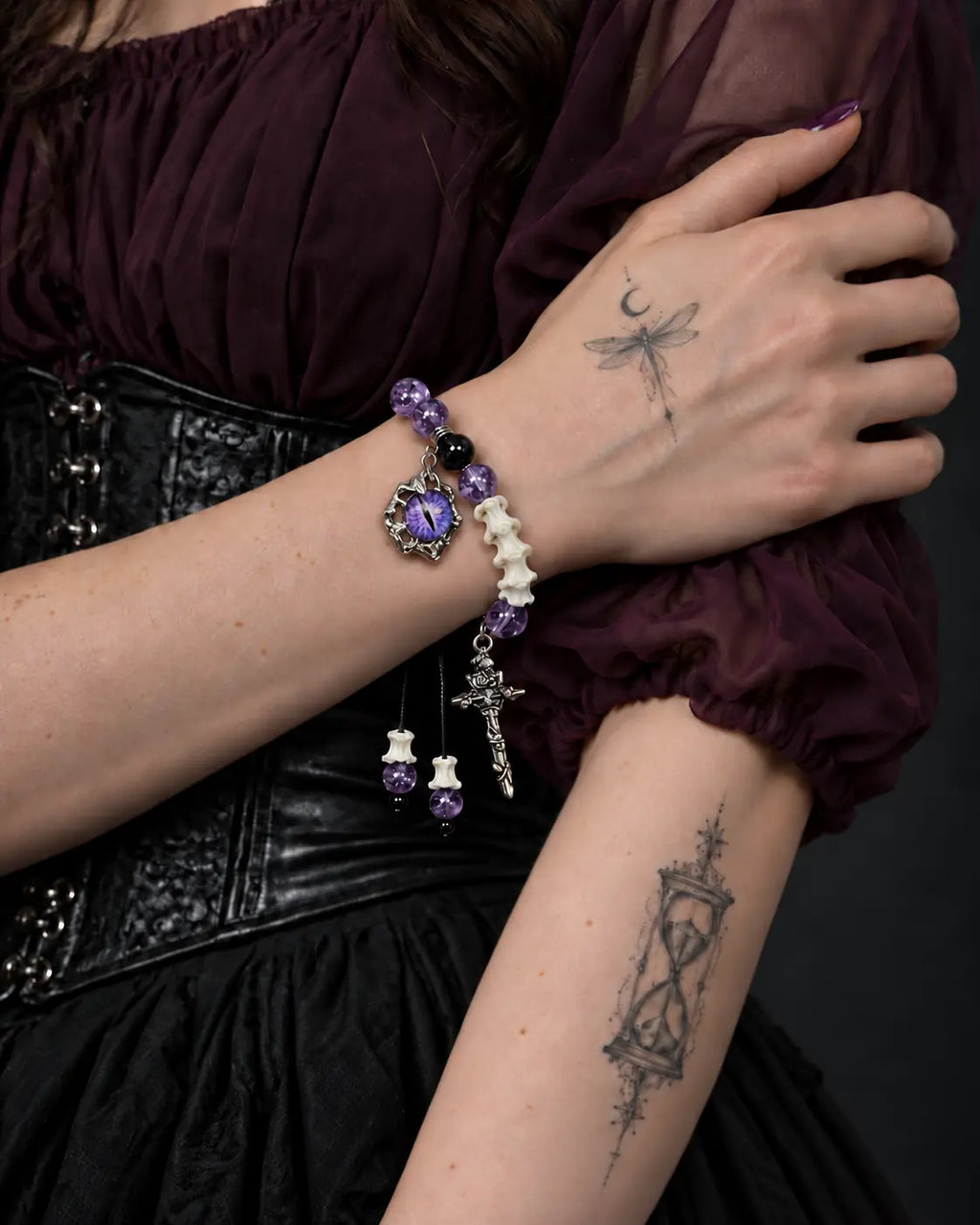 Violet Serpent Eye snake bone bracelet worn with the hand resting across the opposite upper arm
