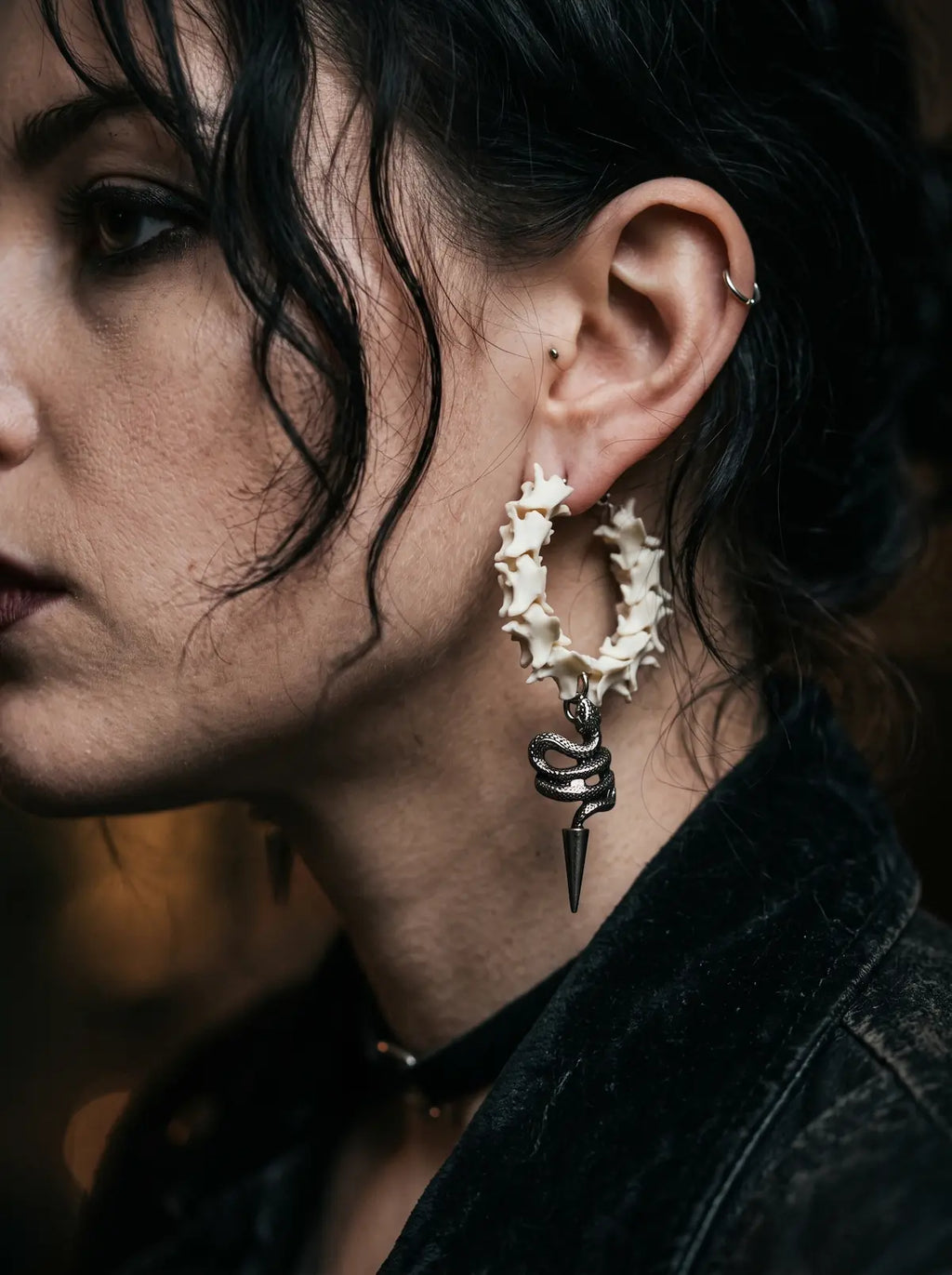 Viper Drop snake bone hoop earring shown in profile against a dark velvet collar