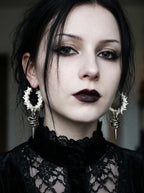 Viper Drop snake bone earrings worn as a pair above a high black lace neckline