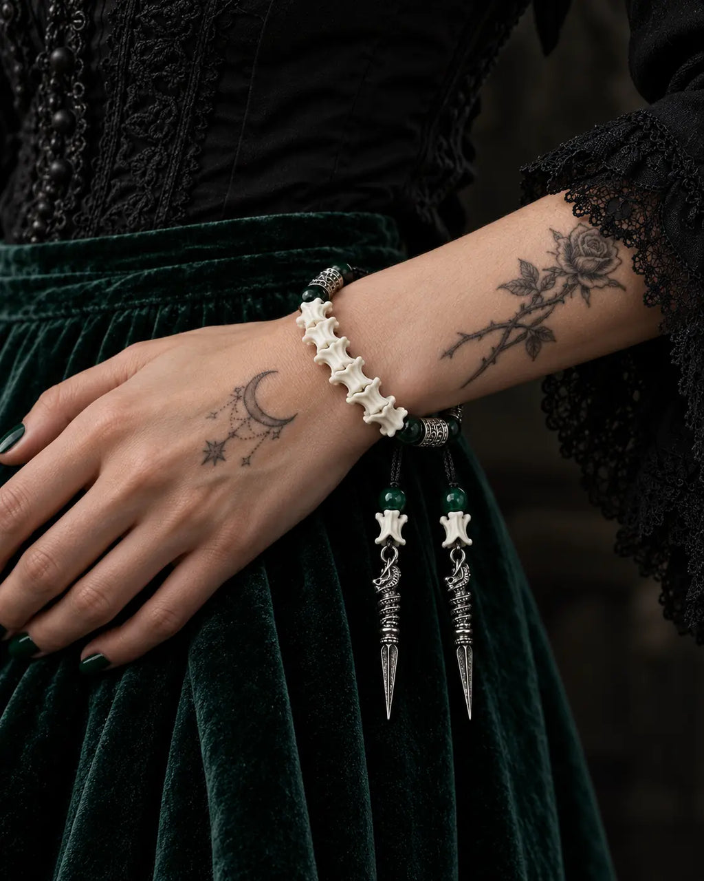 Viridian Wyrm snake bone bracelet worn on a wrist resting against dark green velvet