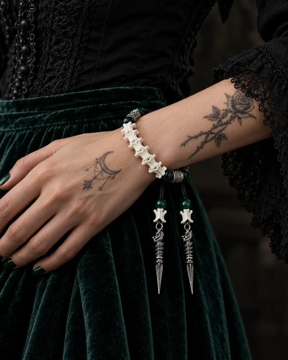 Viridian Wyrm snake bone bracelet worn on a wrist resting against dark green velvet