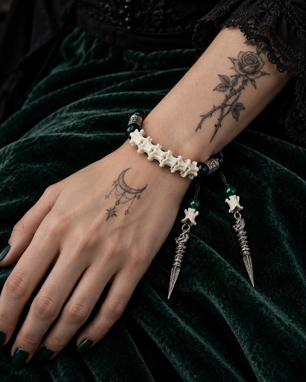 Top view of the Viridian Wyrm snake bone bracelet showing green beads and two long hanging metal drops