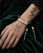 Top view of the Viridian Wyrm snake bone bracelet showing green beads and two long hanging metal drops