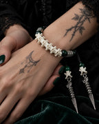 Close-up of the Viridian Wyrm snake bone bracelet showing white vertebrae and engraved silver-tone spacers