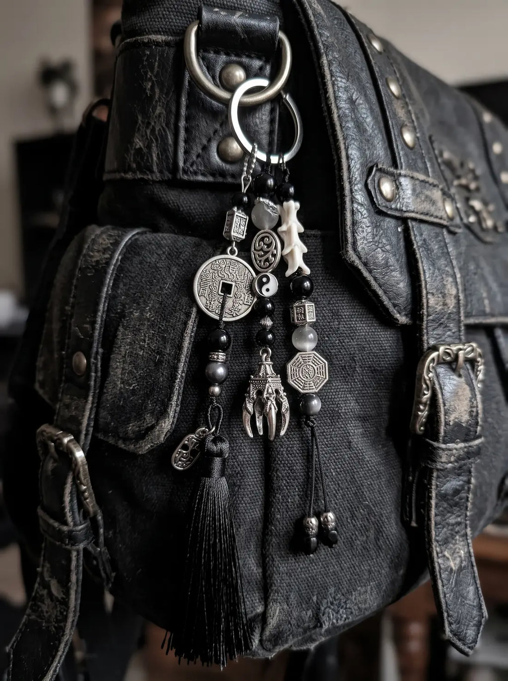 Yin Talisman Snake Bone Keychain, snake bone and coin keychain hanging from the strap of a black leather bag